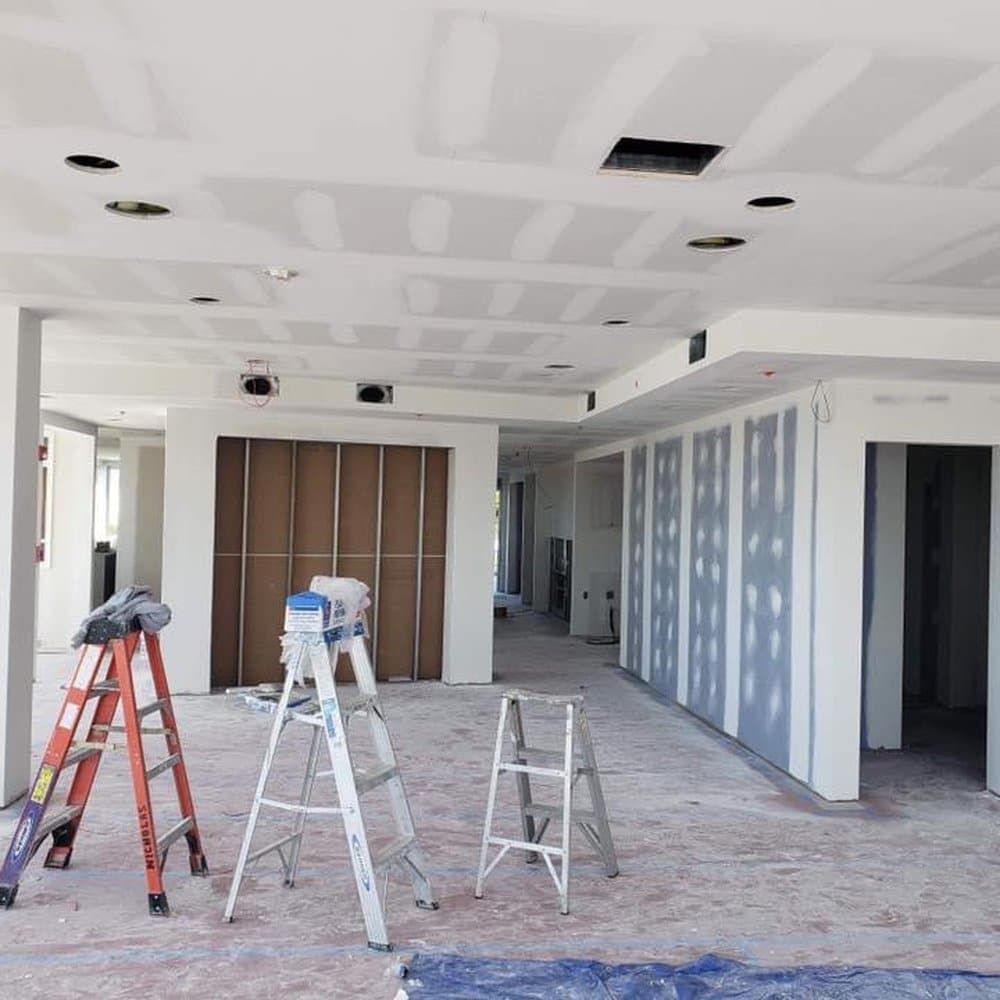 Commercial painters refreshing office hallway walls while protecting floors and door frames